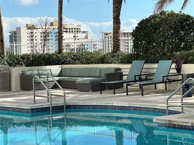 community pool with a patio, fence, an outdoor living space, and a city view