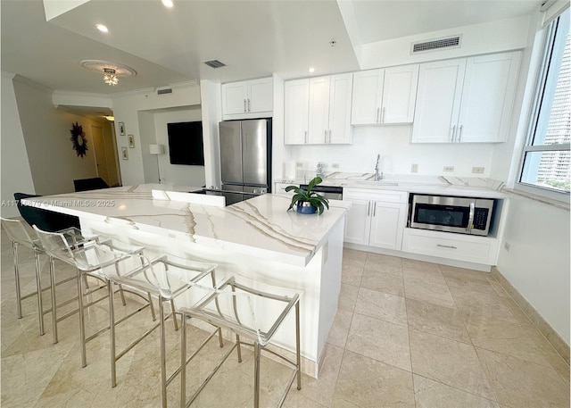 kitchen with a kitchen bar, white cabinets, and stainless steel appliances