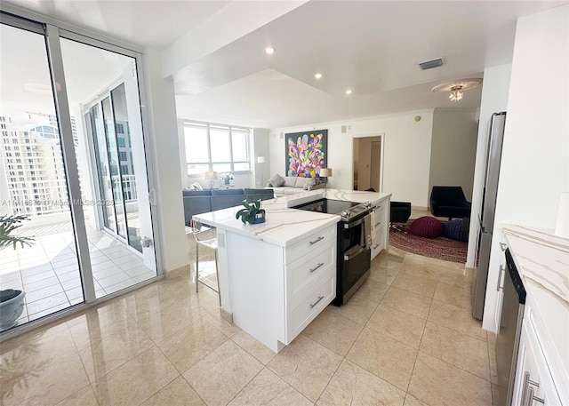 kitchen featuring light stone countertops, appliances with stainless steel finishes, a kitchen island, white cabinetry, and a breakfast bar area