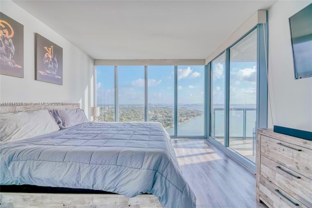 bedroom with multiple windows, access to exterior, hardwood / wood-style flooring, and a wall of windows