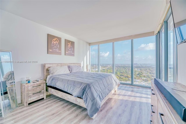 bedroom with a wall of windows and light hardwood / wood-style flooring