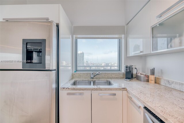 kitchen featuring white cabinets, light stone counters, sink, and stainless steel appliances