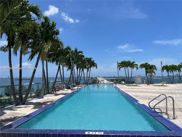 view of swimming pool featuring a water view and a patio