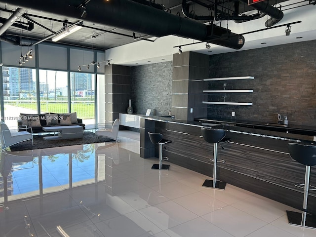 interior space with decorative backsplash, tile patterned flooring, and a towering ceiling