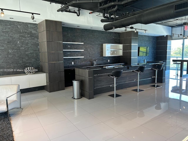 bar featuring light tile patterned floors, tasteful backsplash, and sink