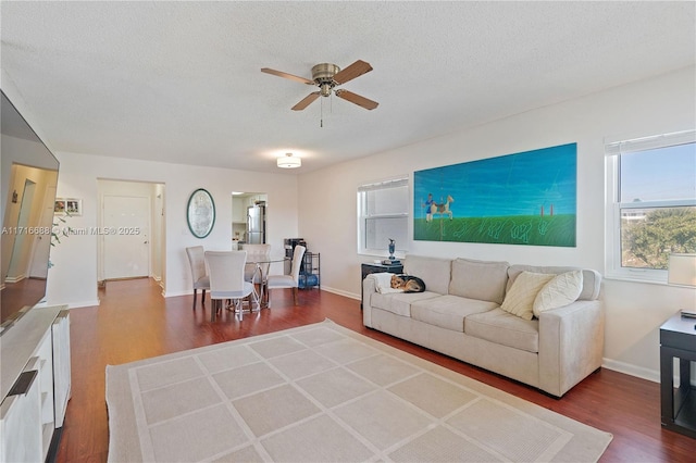 living room featuring wood-type flooring, a textured ceiling, and ceiling fan