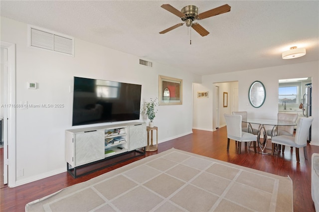 living area featuring ceiling fan, visible vents, a textured ceiling, and wood finished floors