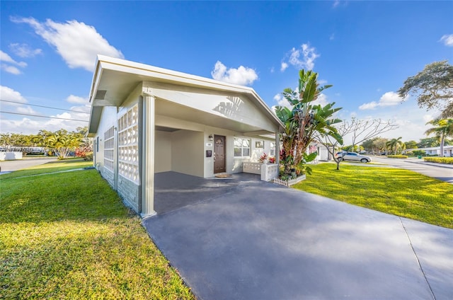 view of side of property with a carport and a lawn