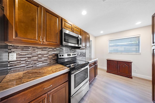 kitchen featuring decorative backsplash, light hardwood / wood-style floors, and appliances with stainless steel finishes