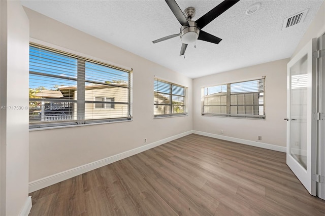 empty room featuring hardwood / wood-style flooring, ceiling fan, and a textured ceiling