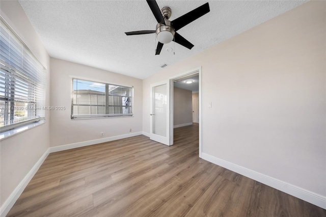 spare room with ceiling fan, light hardwood / wood-style floors, and a textured ceiling