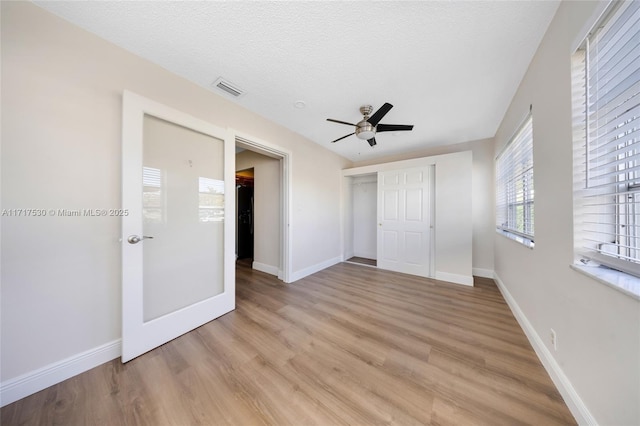 unfurnished bedroom with ceiling fan, a closet, a textured ceiling, and light wood-type flooring