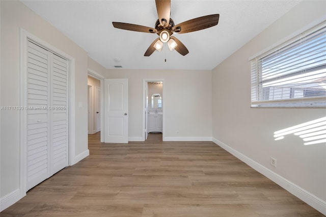 unfurnished bedroom with ceiling fan, light wood-type flooring, connected bathroom, and a closet