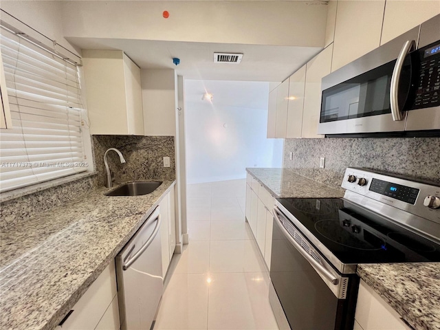 kitchen featuring sink, light tile patterned floors, appliances with stainless steel finishes, tasteful backsplash, and white cabinetry