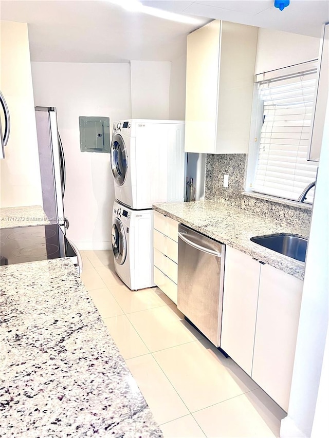 1881 Washington Ave Unit 11D, Miami Beach, FL 33139 - kitchen with stacked washing machine and dryer, light tile patterned flooring, stainless steel appliances, light stone countertops, and electric panel