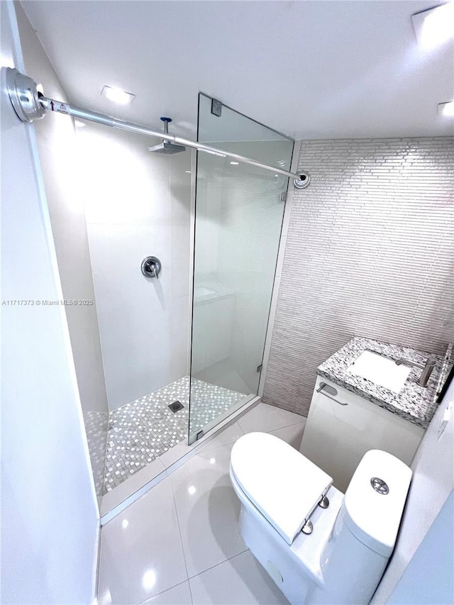 bathroom with a tile shower, toilet, sink, and tile patterned flooring