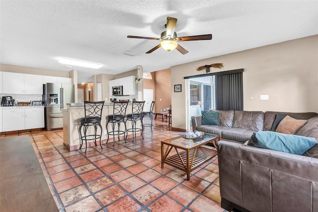 living room with a textured ceiling, tile patterned floors, and ceiling fan