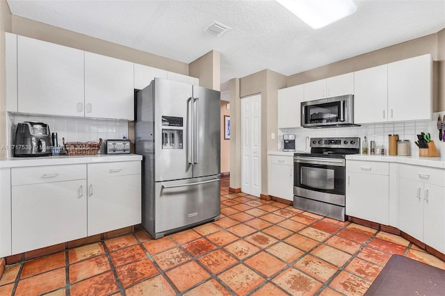 kitchen featuring appliances with stainless steel finishes, a textured ceiling, tasteful backsplash, and white cabinetry