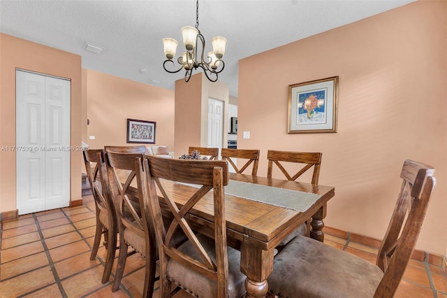 dining room featuring light tile patterned floors, a textured ceiling, and an inviting chandelier