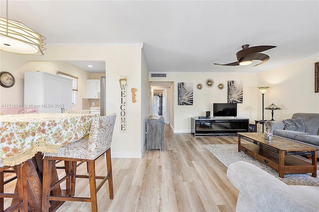 living room featuring light hardwood / wood-style floors, ceiling fan, and ornamental molding