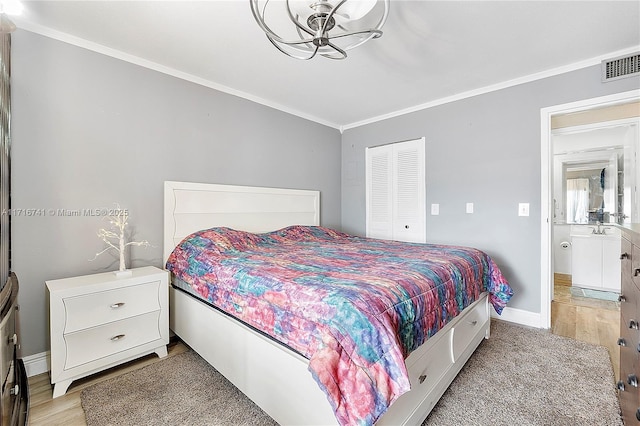 bedroom featuring light hardwood / wood-style flooring, ensuite bath, a closet, and crown molding