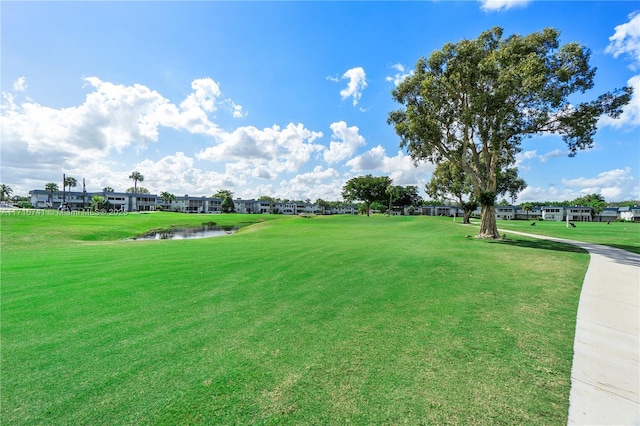 view of property's community with a water view and a lawn