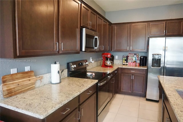 kitchen featuring light stone countertops, dark brown cabinets, light tile patterned floors, and stainless steel appliances