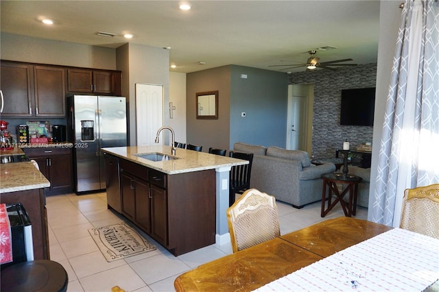 kitchen featuring light stone counters, stainless steel appliances, a kitchen island with sink, sink, and light tile patterned floors