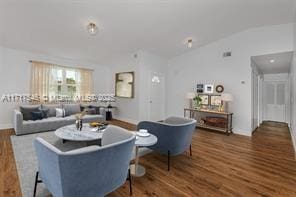 living room with dark wood-type flooring and vaulted ceiling