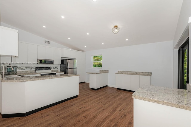 kitchen with appliances with stainless steel finishes, backsplash, sink, white cabinetry, and lofted ceiling