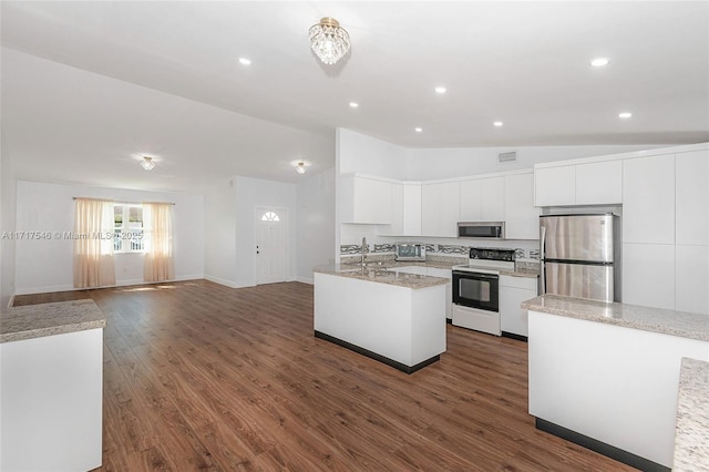 kitchen featuring appliances with stainless steel finishes, dark hardwood / wood-style flooring, light stone counters, white cabinets, and lofted ceiling