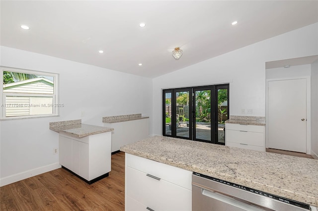 kitchen featuring a healthy amount of sunlight, vaulted ceiling, white cabinetry, and stainless steel dishwasher