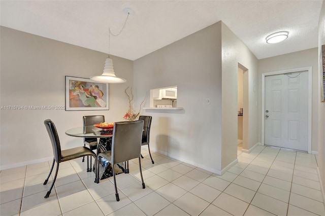 dining space featuring a textured ceiling and light tile patterned flooring