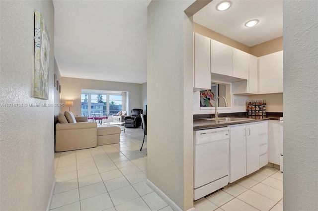 kitchen with white dishwasher, light tile patterned flooring, white cabinets, and sink