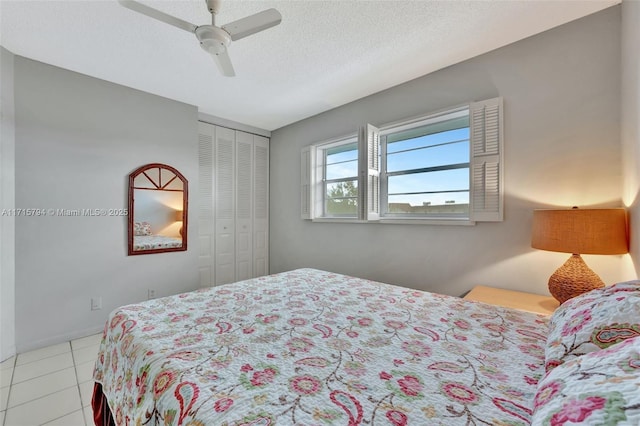 bedroom featuring light tile patterned flooring, a textured ceiling, a closet, and ceiling fan