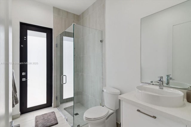 bathroom with tile patterned flooring, vanity, toilet, and a shower with shower door