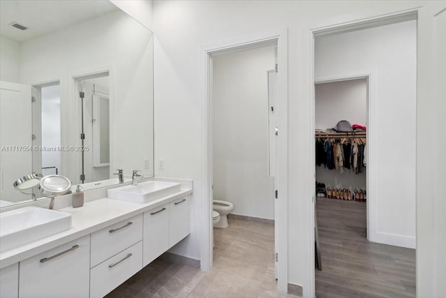 bathroom featuring vanity, toilet, wood-type flooring, and a bidet