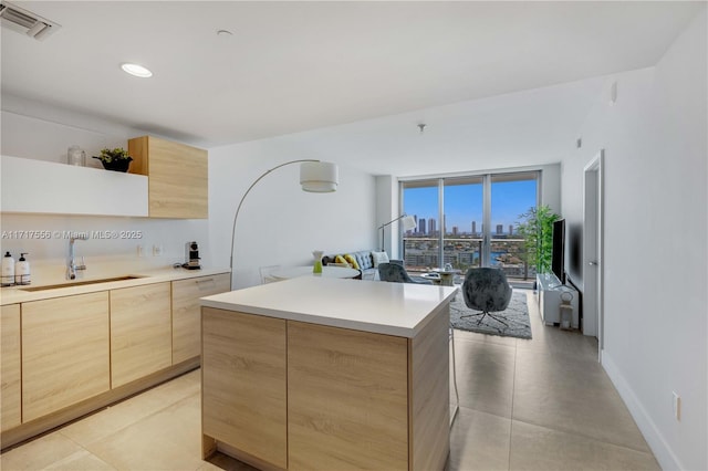 kitchen featuring light brown cabinetry, a kitchen island, expansive windows, and sink