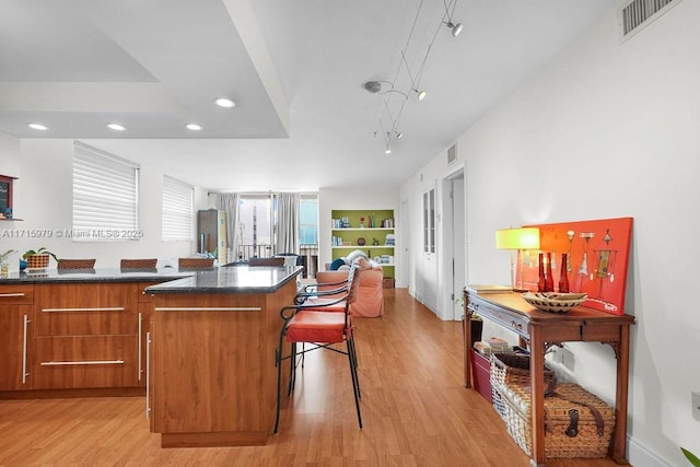 kitchen featuring a kitchen breakfast bar, built in shelves, a center island, and light wood-type flooring