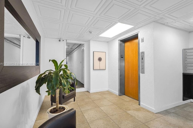 corridor featuring elevator, light tile patterned floors, and a mail area