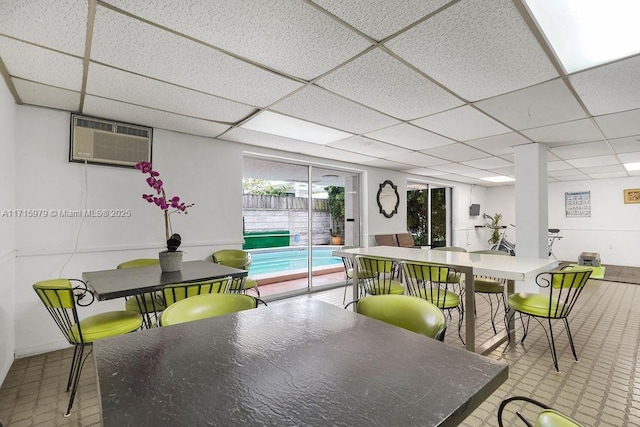 dining area with a drop ceiling and a wall mounted AC