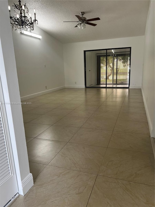 empty room featuring ceiling fan with notable chandelier and a textured ceiling