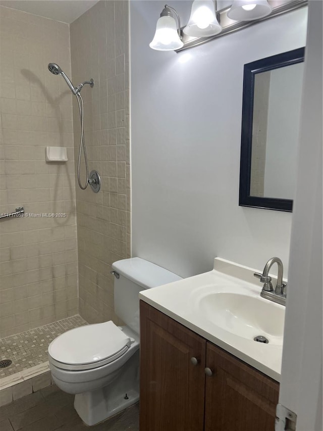 bathroom featuring tiled shower, vanity, and toilet