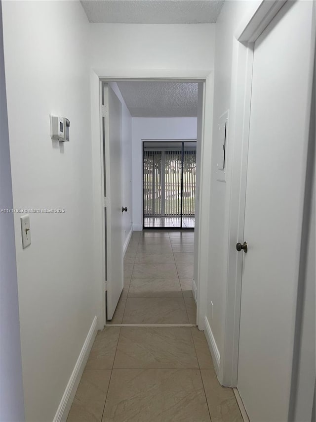 corridor with light tile patterned floors and a textured ceiling