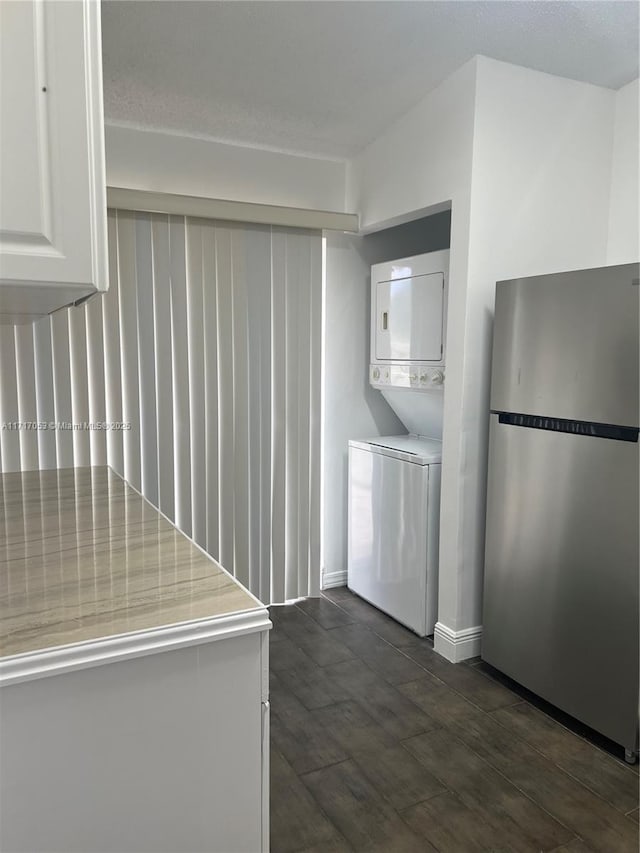 laundry room featuring dark hardwood / wood-style flooring and stacked washing maching and dryer