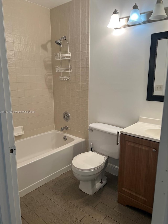 full bathroom with vanity, hardwood / wood-style floors, tiled shower / bath combo, and toilet