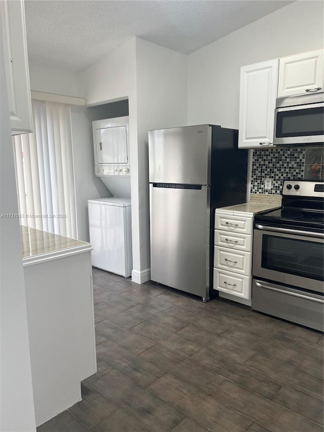 kitchen with decorative backsplash, a textured ceiling, stainless steel appliances, stacked washer and clothes dryer, and white cabinets