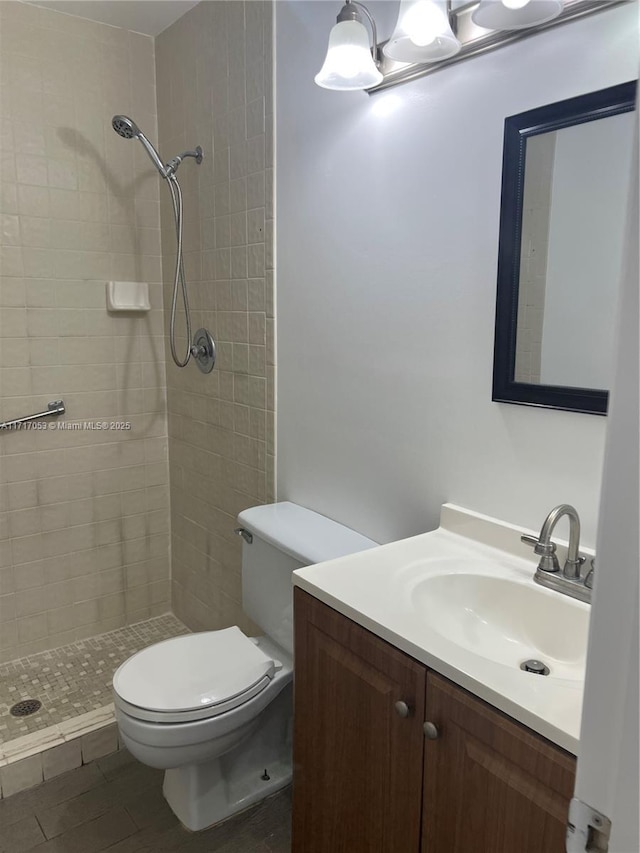 bathroom with a tile shower, vanity, and toilet