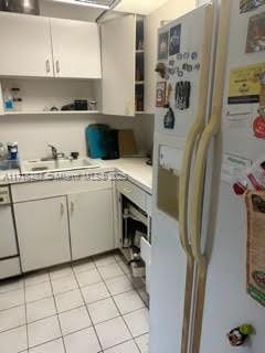 kitchen with white cabinetry, sink, light tile patterned floors, and white appliances