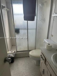 bathroom with tile patterned floors, vanity, an enclosed shower, and toilet